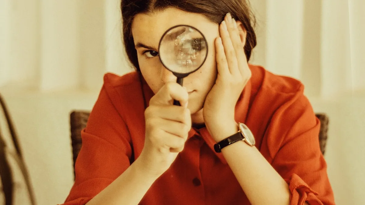A person examining details through a magnifying glass, representing the scrutiny needed before buying a timeshare