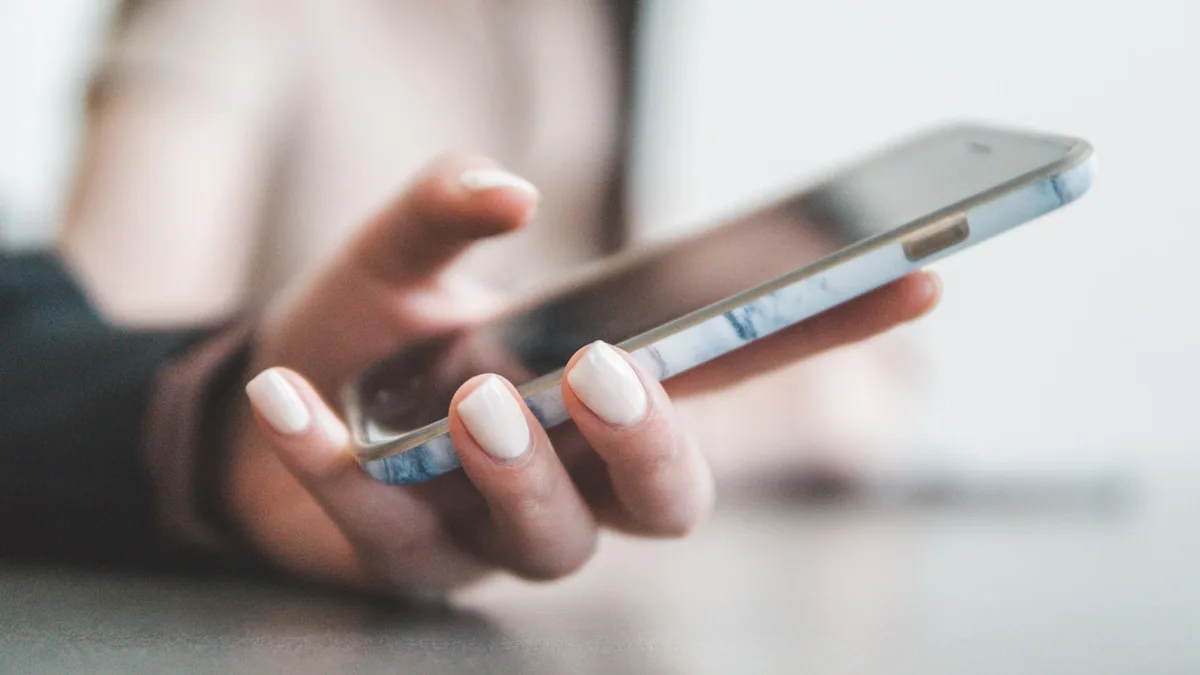 A hand holding a smartphone, representing the unsolicited cold calls that begin most timeshare exit scams targeting U.S. owners