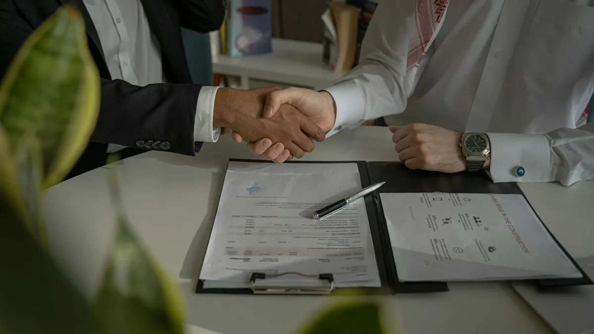 Two people shaking hands over a signed written agreement at a desk, representing a verified and legitimate U.S. timeshare exit company
