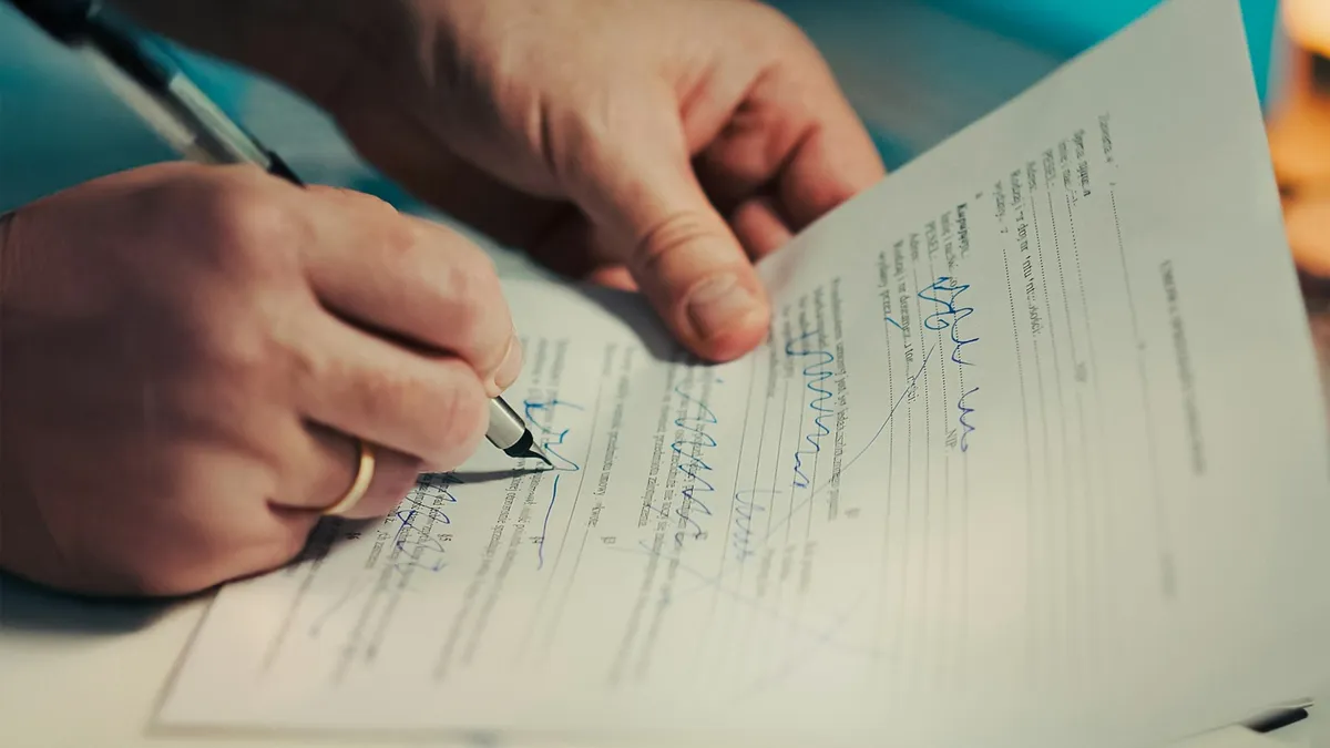 Close-up of hands signing a printed legal document with a pen, representing the transfer paperwork a U.S. timeshare owner completes during a deed back