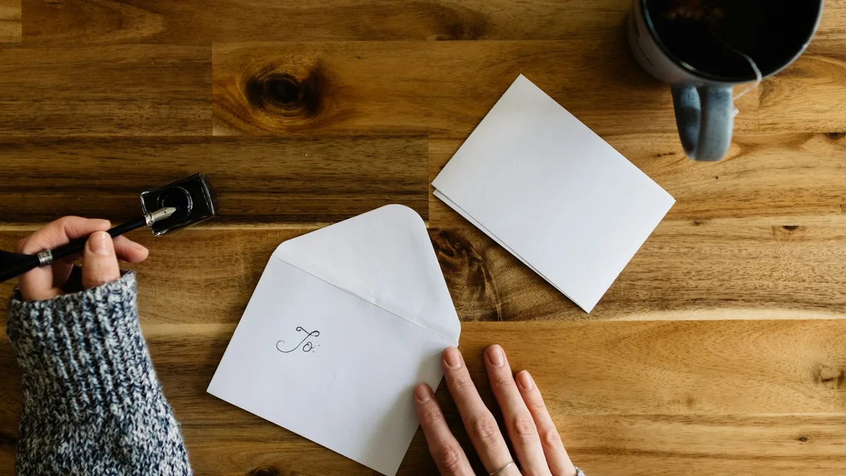 An envelope, notepaper, and pen laid out on a desk, representing the written dispute letter a U.S. timeshare owner sends by certified mail