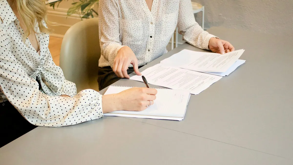 Two people seated at a desk reviewing contract paperwork and taking notes, representing a U.S. heir going over timeshare documents with a professional