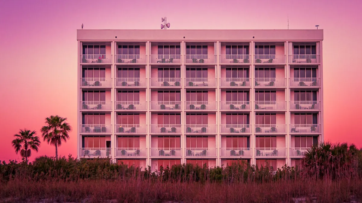 A beachfront resort building lined with balconies under a pink sunset sky, representing the U.S. vacation property that carries inherited timeshare obligations