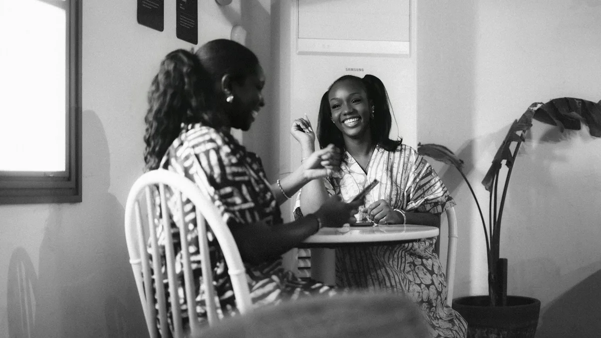 Two people talking warmly across a small table, representing a U.S. owner discussing a timeshare transfer with a family member or friend before signing