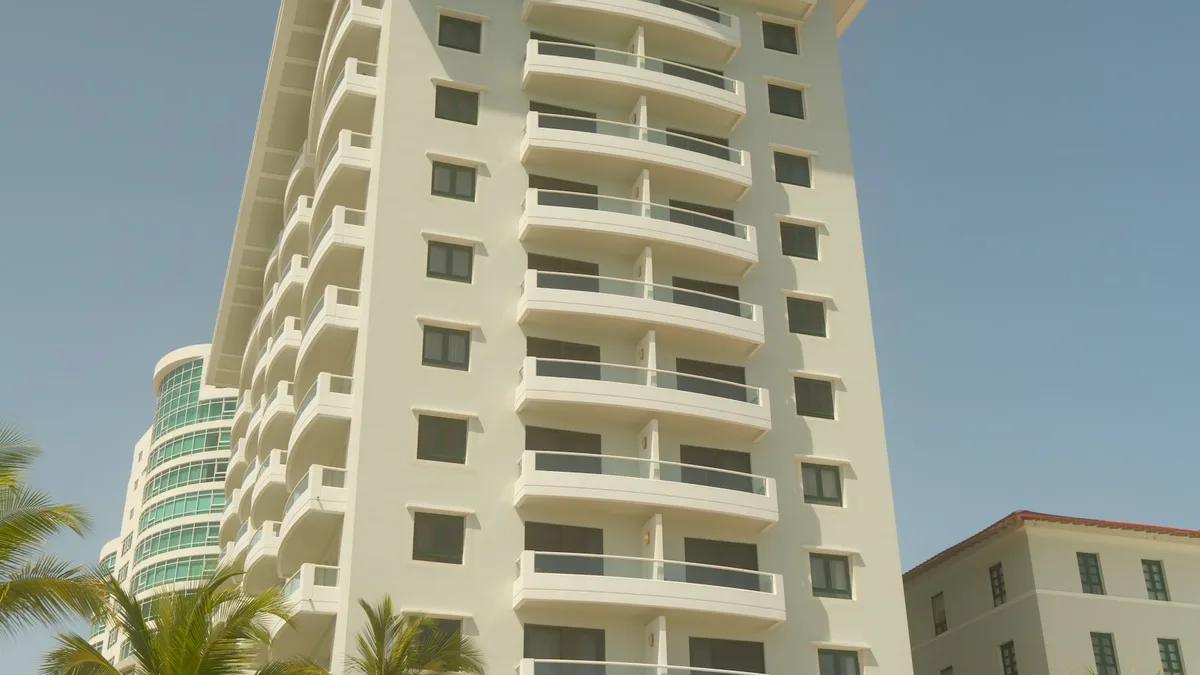 A beachfront resort tower with tiered balconies framed by palm trees, representing the shared vacation units U.S. timeshare owners hold an interest in