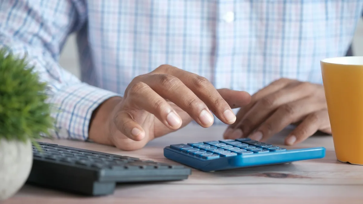A person working through figures on a calculator at a desk, representing the maintenance fee math that deters U.S. timeshare resale buyers