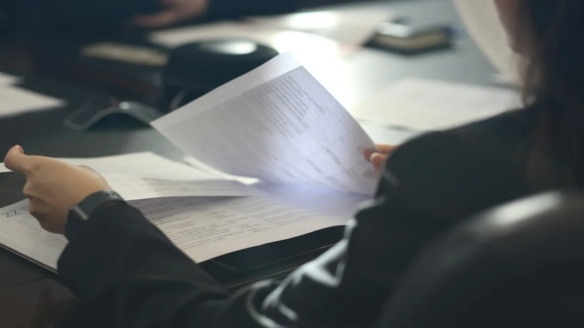 A person reviewing pages of a printed agreement at a desk, representing a U.S. timeshare owner documenting misrepresentation and examining contract terms