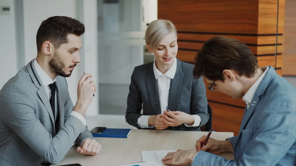 Three professionals reviewing and signing paperwork across a conference table, representing documented negotiation with a resort after a timeshare default