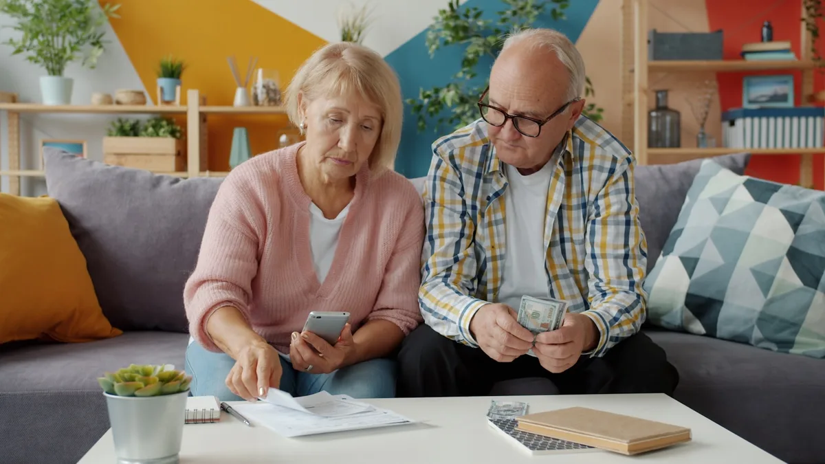 An older couple reviewing bills and household finances at home, representing U.S. timeshare owners facing financial hardship on a fixed income