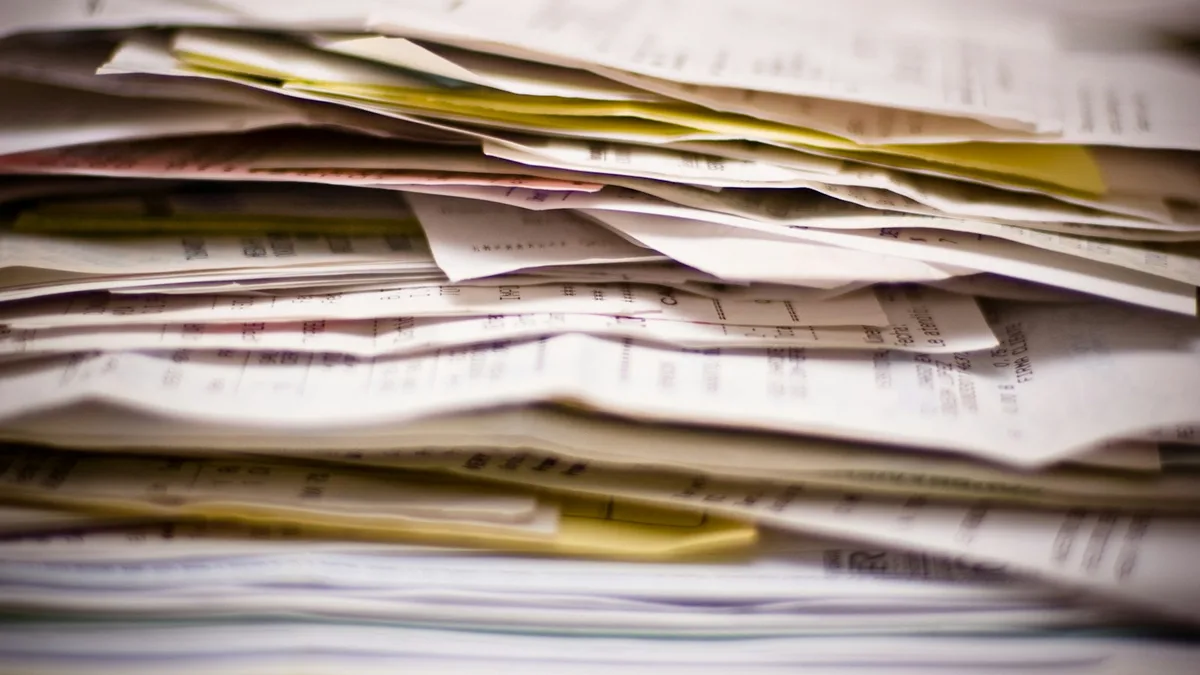 A thick stack of invoices and statements piled on a desk, representing the annual maintenance fees and special assessments that accumulate for timeshare owners