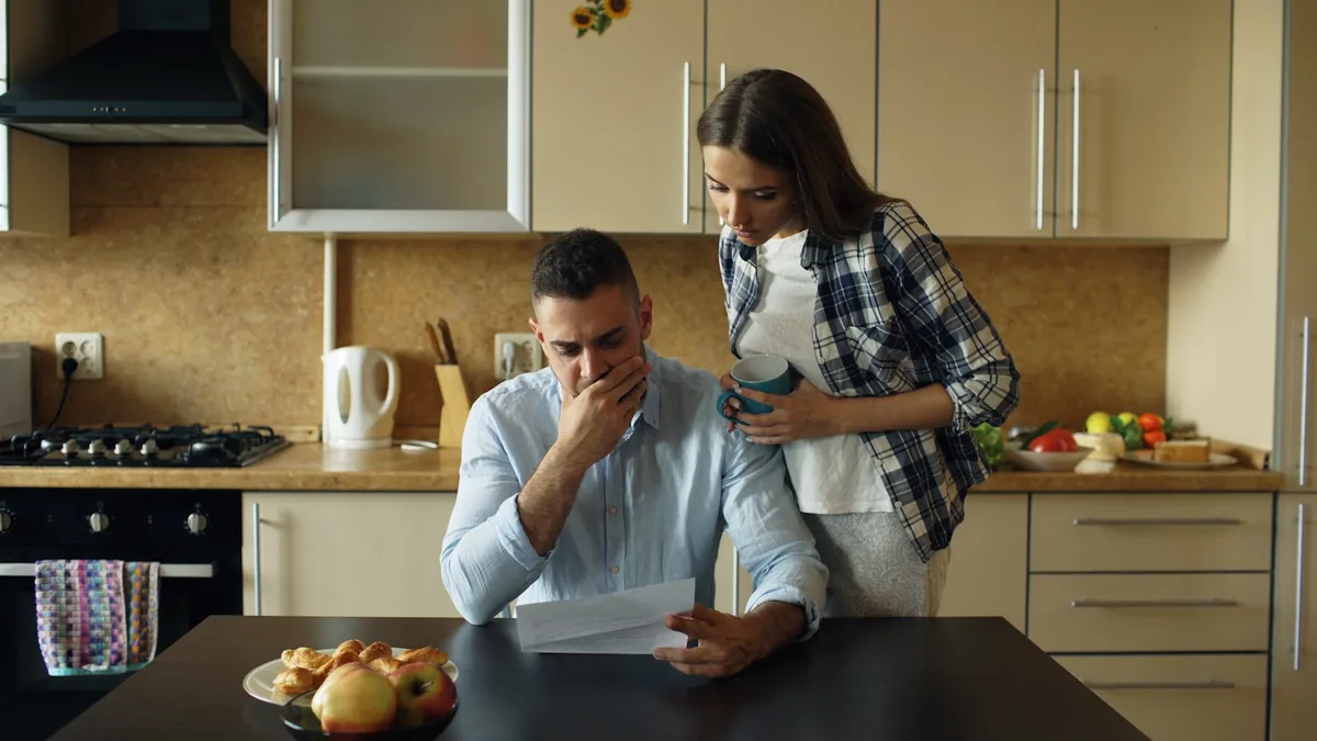 A concerned couple reading a letter together at their kitchen table, representing U.S. owners receiving a delinquency or collection notice from a resort