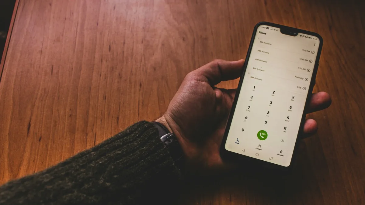 A hand holding a phone showing a call log of repeated unsolicited calls, representing the cold-contact tactic behind many timeshare resale scams
