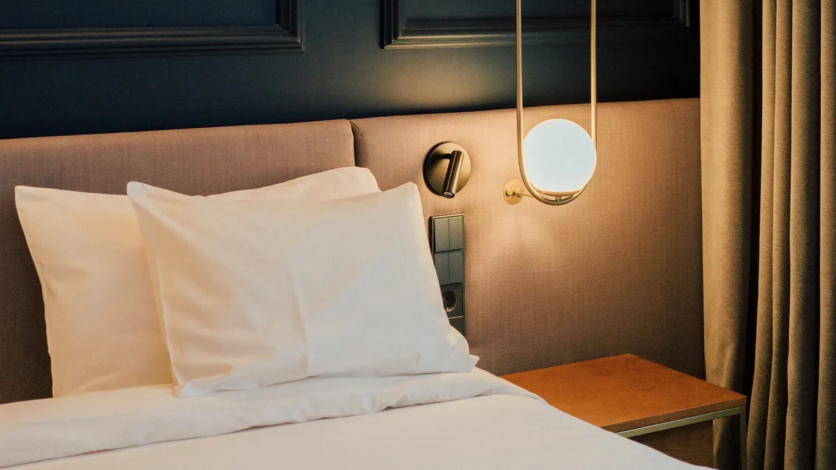 A made-up, empty resort room with turned-down bedding and a bedside lamp, representing a timeshare week that sits unused while fees continue to accrue
