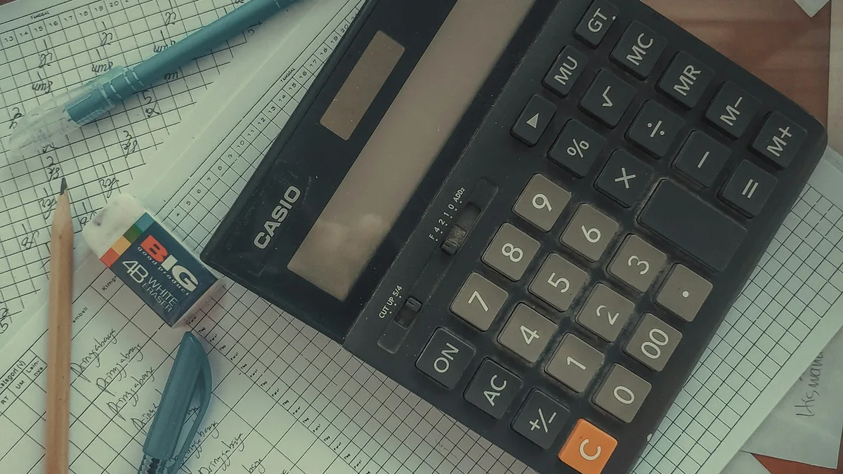 A calculator resting on handwritten ledger sheets, representing the rising annual maintenance fees U.S. timeshare buyers subtract from any resale offer