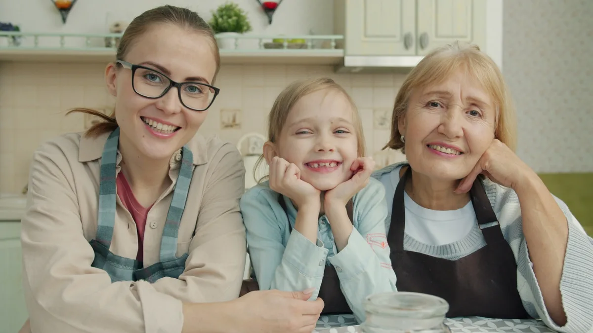 Three generations of one family smiling together in a kitchen, representing a U.S. owner gifting or transferring a timeshare to a family member