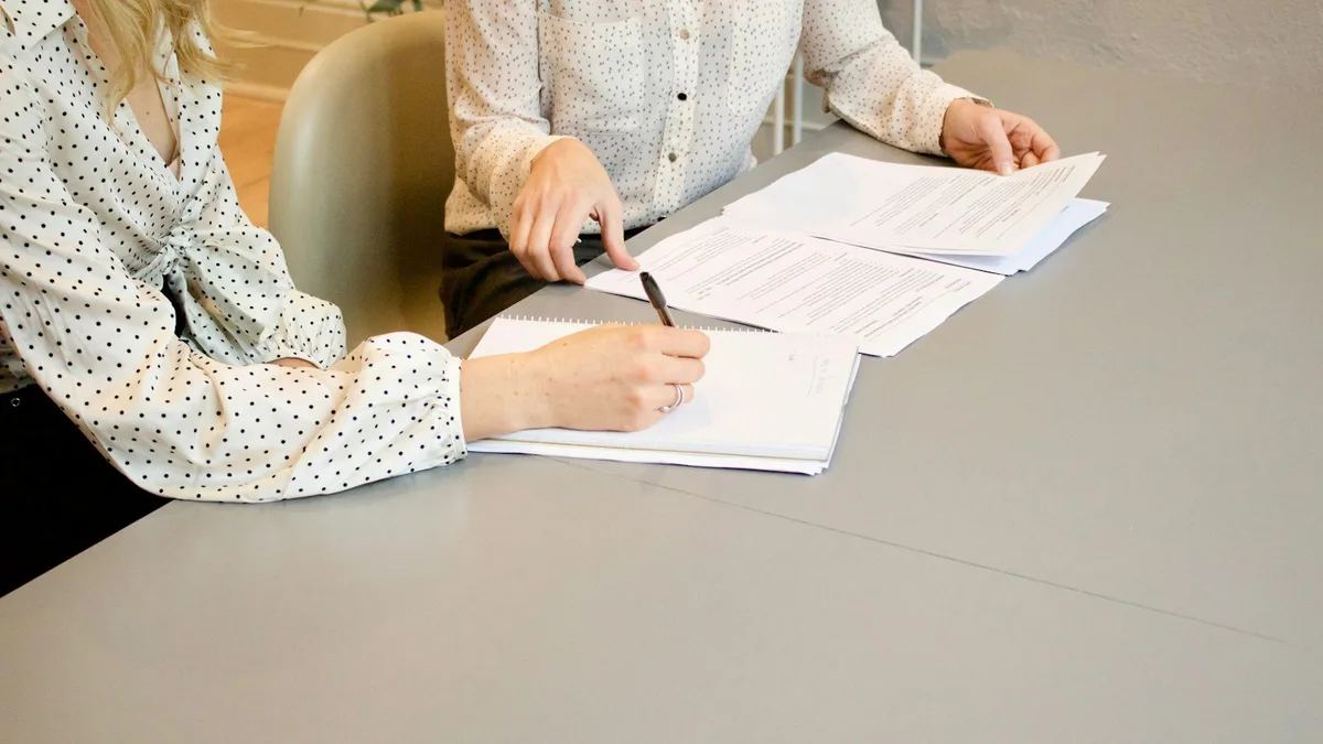 Two people reviewing and signing contract paperwork at a desk, representing professional help for U.S. timeshare owners pursuing a legal exit